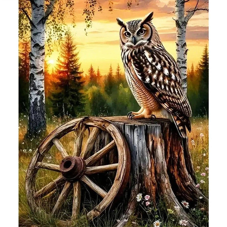 Broderie diamant d'un hibou grand-duc perché sur une souche près d'une roue de charrette, devant un coucher de soleil